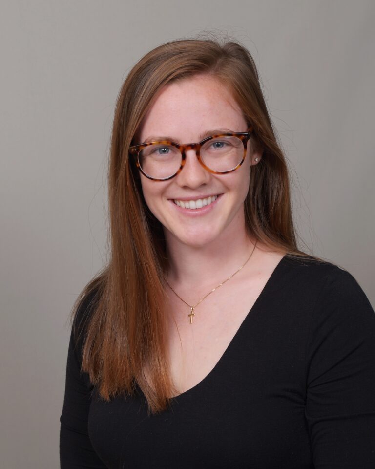 Headshot of Dr. Maggie Gentine wearing black long sleeve and eyeglasses against a plain gray background.